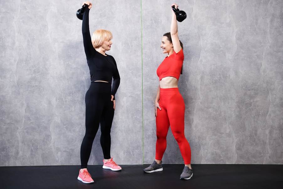 Two women lifting kettlebells in a fitness workout.
