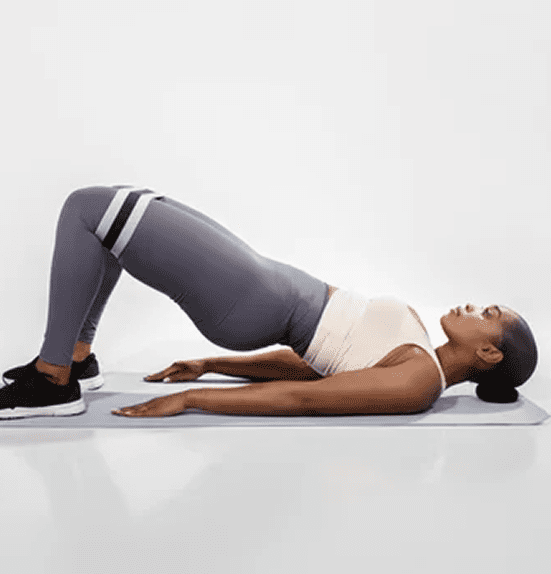 Woman performing a glute bridge exercise on a mat.
